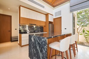 Uma cozinha moderna com ilha de mármore, armários de madeira e geladeira embutida.
