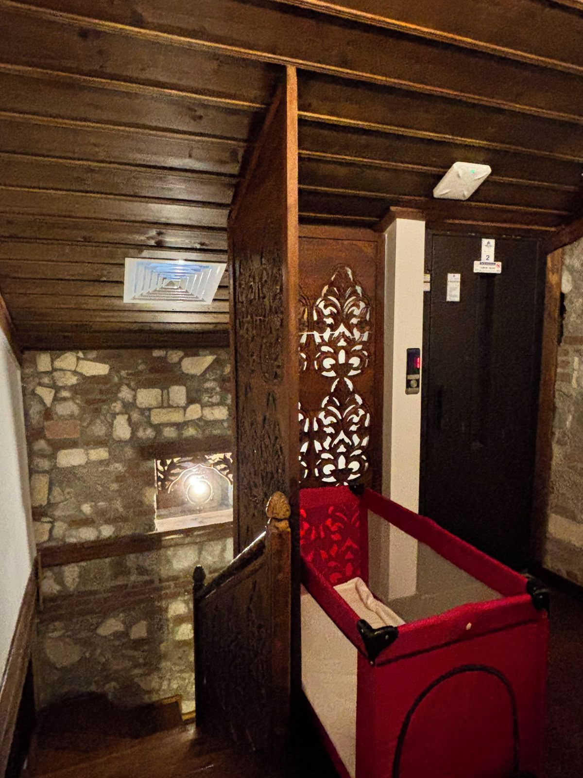 Una escalera estrecha con un muro de piedra a un lado y una puerta de madera al otro.