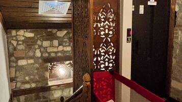 Una escalera estrecha con un muro de piedra a un lado y una puerta de madera al otro.