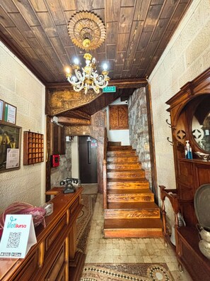 A wooden staircase with a chandelier, a sign indicating an exit, and a patterned floor. - DuruHanımKonağı (Mudanya)