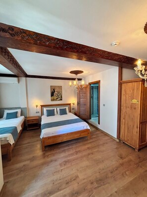 A bedroom with two beds, a wooden wardrobe, a chandelier, and a painting on the wall. - DuruHanımKonağı (Mudanya)