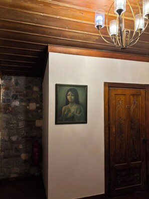 A room with a wooden ceiling, a stone wall, a framed painting, and a wooden door. - DuruHanımKonağı (Mudanya)