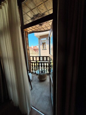 Un balcón con una mesa de vidrio y vista a un edificio con ventana.