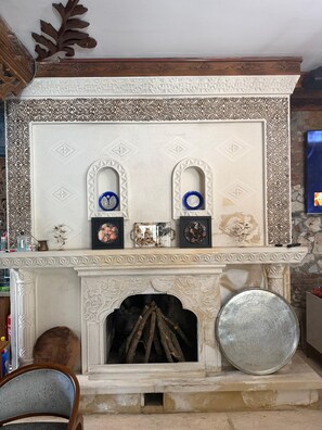 Una chimenea con elaborados diseños blancos y marrones, un repisa con obras de arte enmarcadas y una pared de piedra.