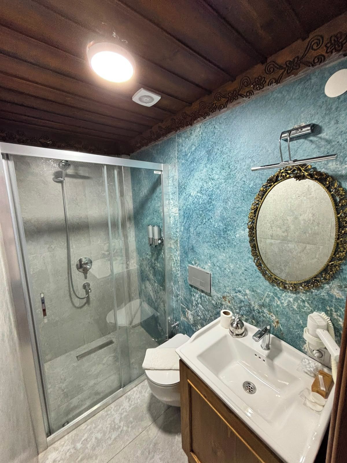 A bathroom with a glass shower enclosure, a toilet, a sink with a mirror, and a towel rack.