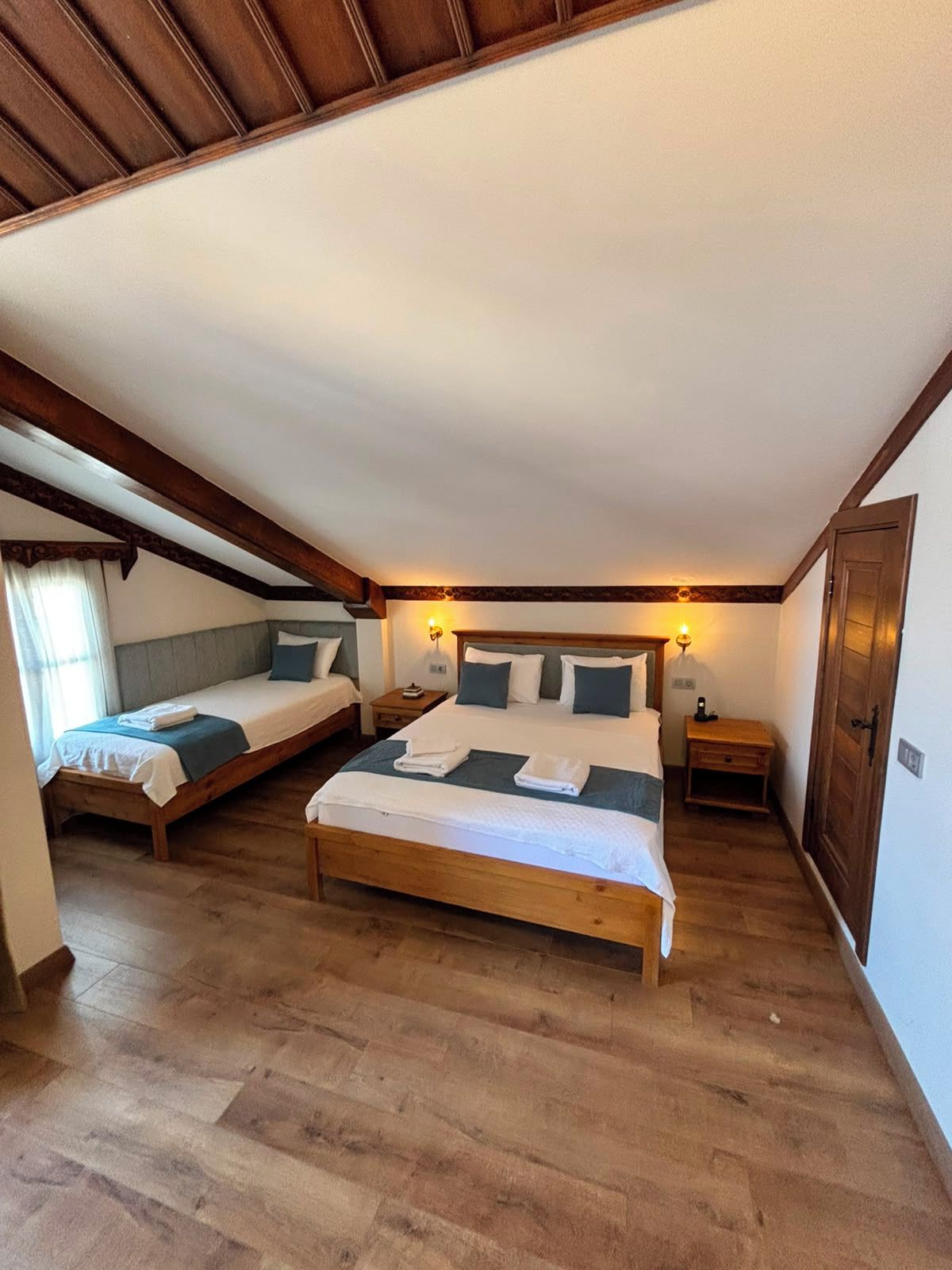 Un dormitorio con dos camas, suelo de madera y techo inclinado.
