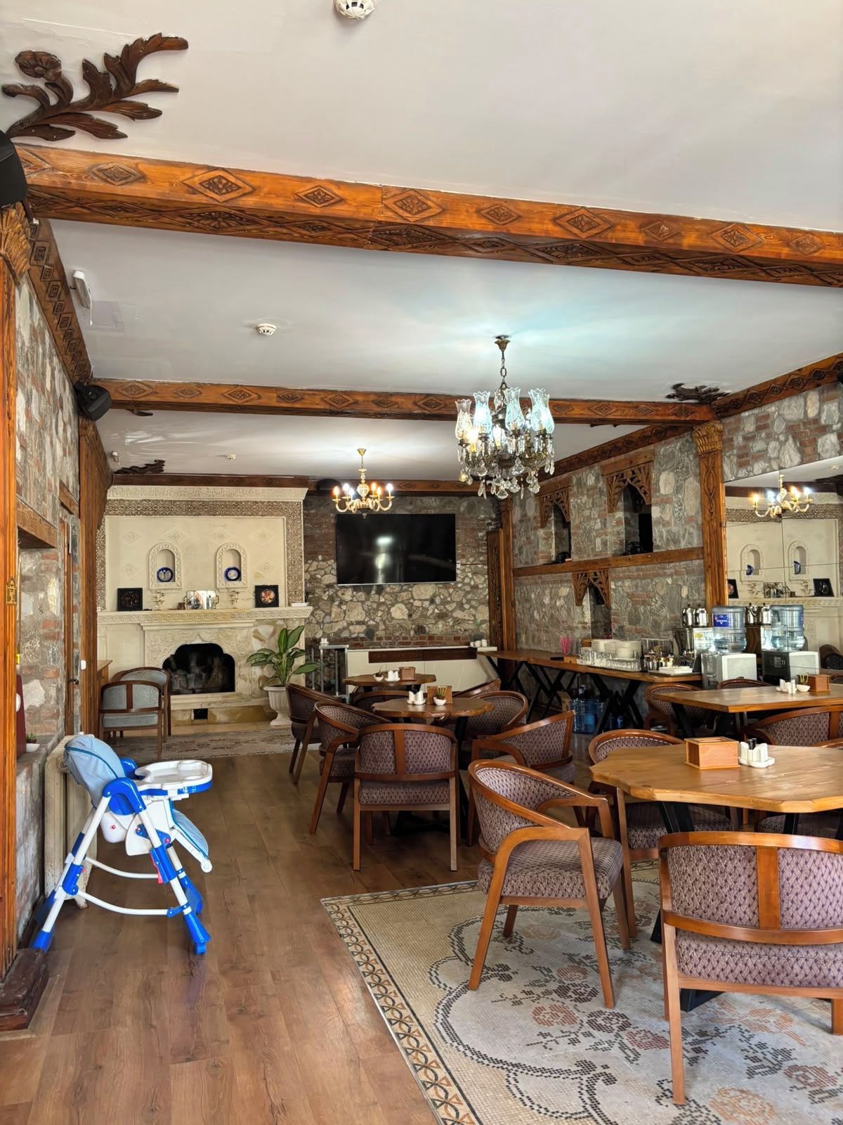 A dining area with wooden furniture, a chandelier, and a stone fireplace.