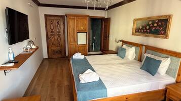 Un dormitorio con una cama de madera, un televisor, una araña y un cuadro en la pared.