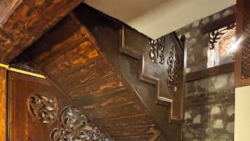 Una escalera de madera con tallas intrincadas y una pared de piedra.