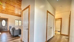 A hallway with wooden flooring, white walls, and two white doors with wooden frames. - The Sunflower Cabin - Pets, Continuous hot water, Traeger grill, Starlink, AC (Overgaard)