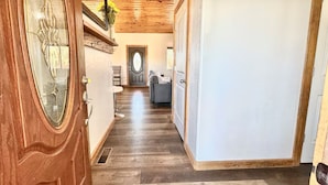 A hallway with wooden flooring, a door with a glass panel, and a mirror. - The Sunflower Cabin - Pets, Continuous hot water, Traeger grill, Starlink, AC (Overgaard)