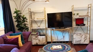A modern living room with purple sofas, a flat-screen TV, and a decorative plant. - UPSCALE EAST TEXAS CABIN, PRIVATE HOT TUB, WIFI, ROKU, OLD MILL VILLAGE KENNARD (Kennard)