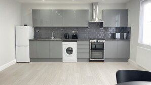 Une cuisine moderne avec des meubles gris, un lave-linge encastré, un four à micro-ondes et une cuisinière.