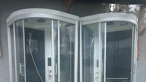 Una vasca da bagno angolare con porte in vetro e un soffione.