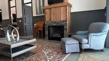 A modern living room with a fireplace, a television mounted on the wall, and a large rug.