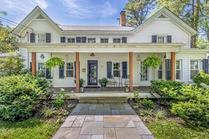 A two-story house with a front porch, a number '51' sign, and a well-maintained garden.