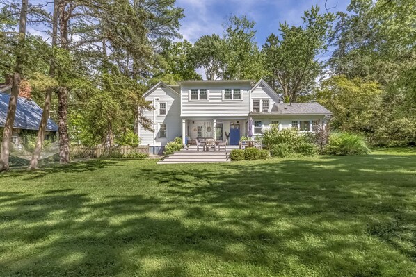 A two-story house with a front porch, a small deck, and a well-maintained lawn.