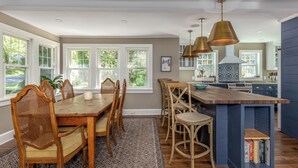 A spacious kitchen with a wooden dining table, chairs, and a built-in island with a bookshelf. - Beautiful 3-bedroom house in New Paltz with AC, WiFi, SunDeck & Close to ALL (New Paltz)