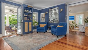 A spacious living room with blue walls, wooden flooring, and a large sailboat painting. - Beautiful 3-bedroom house in New Paltz with AC, WiFi, SunDeck & Close to ALL (New Paltz)