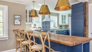 A kitchen with a wooden island, three wicker chairs, and pendant lights. - Beautiful 3-bedroom house in New Paltz with AC, WiFi, SunDeck & Close to ALL (New Paltz)