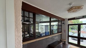 A room with a large window, a dark wood floor, a bench, and a wall-mounted light fixture. - The Queens Road Hotel (Shanklin)