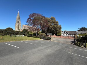 A parking lot with a church and residential buildings in the background.