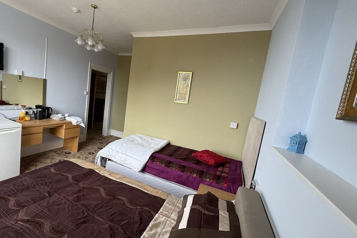 A compact hotel room with a bed, a desk, a refrigerator, and a television.