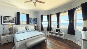 A bedroom with a bed, bench, bedside tables, and a ceiling fan.
