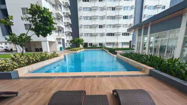 A swimming pool with lounge chairs and a view of high-rise buildings. - NYC Vibes! 1-BR Condo in BGC with Pool, AC, Hi-Speed WiFi, Netflix! Sleeps 2-3 (Taguig City)