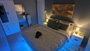 A bedroom with a bed, bedside tables, a wardrobe, and a large wall-mounted artwork. - NYC Vibes! 1-BR Condo in BGC with Pool, AC, Hi-Speed WiFi, Netflix! Sleeps 2-3 (Taguig City)