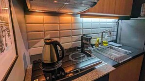 A kitchen with a stove, kettle, and sink. - NYC Vibes! 1-BR Condo in BGC with Pool, AC, Hi-Speed WiFi, Netflix! Sleeps 2-3 (Taguig City)