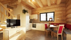 A modern log cabin interior with a wooden dining area, kitchen, and a large window. - Cosy Chalet with Panoramic View, Sun Terrace and Free Summer Mountain Cable Car (Ladis)