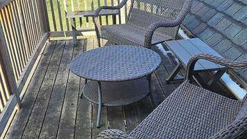 Une terrasse en bois avec des meubles en osier, notamment deux chaises et une petite table.
