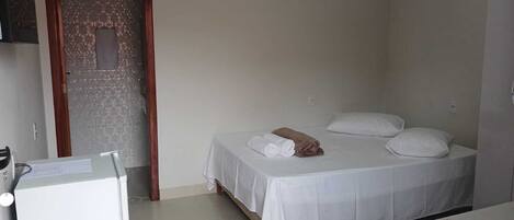 A small, clean room with a bed, a desk, and a door.