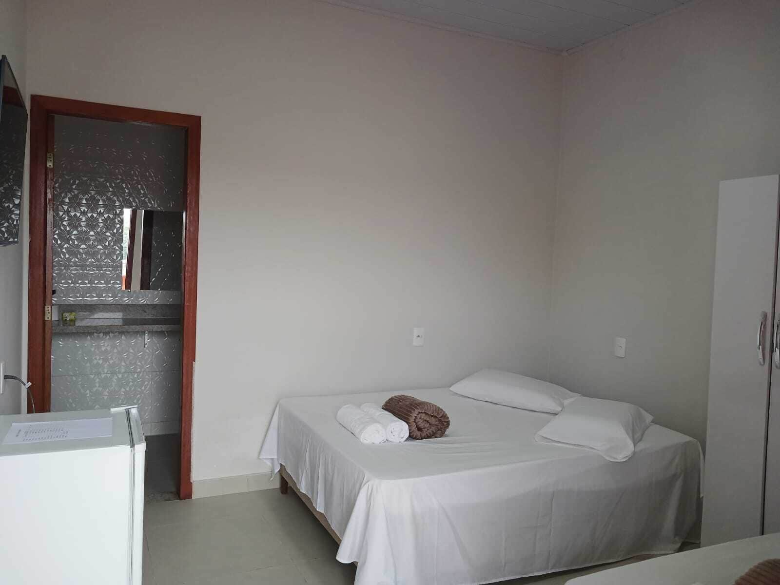 A small, clean room with a single bed, a wardrobe, and a mirror.