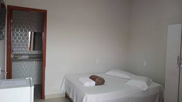 Quarto pequeno e limpo com uma cama de solteiro, um guarda-roupa e um espelho.