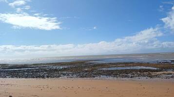 Uma praia com céu claro e algumas nuvens.