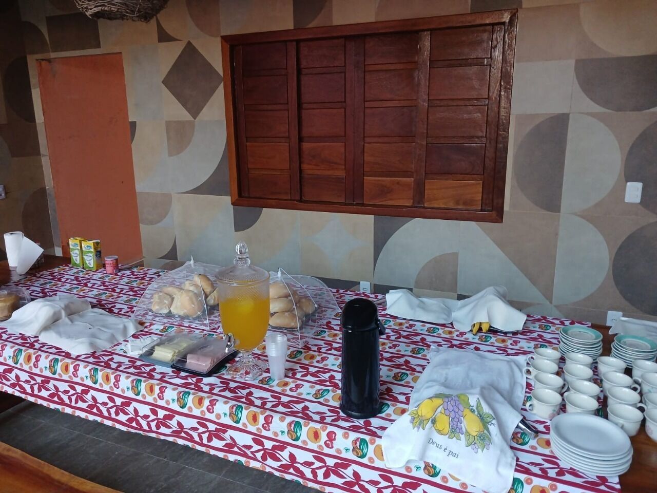A buffet setup with various food items, a beverage dispenser, and stacked plates.