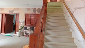 A staircase with wooden handrails, a dining area with chairs and a table, and a door leading to another room. - Pousada Jubarte (Serra)