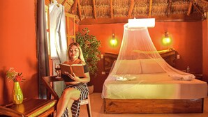 A room with a bed, a chair, a table, and a vase with flowers. - Hotel Aldea Cruzo'ob (Felipe Carrillo Puerto)