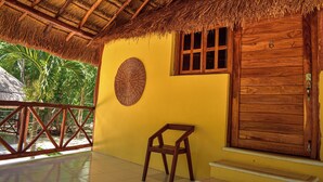 A wooden cabin with a thatched roof, a wooden door, and a window with a grid pattern. - Hotel Aldea Cruzo'ob (Felipe Carrillo Puerto)