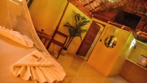 A hotel room with a bed, a chair, a potted plant, a mirror, and a television. - Hotel Aldea Cruzo'ob (Felipe Carrillo Puerto)