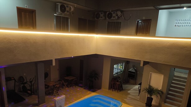 Ein mehrgeschossiges Innenraumareal mit Schwimmbad, Fitnessgeräten und Grillplatz.
