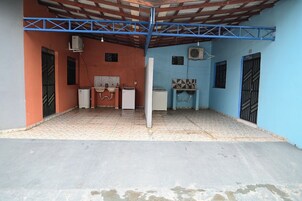 Un espacio exterior techado con piso de baldosas, un lavamanos y un refrigerador.