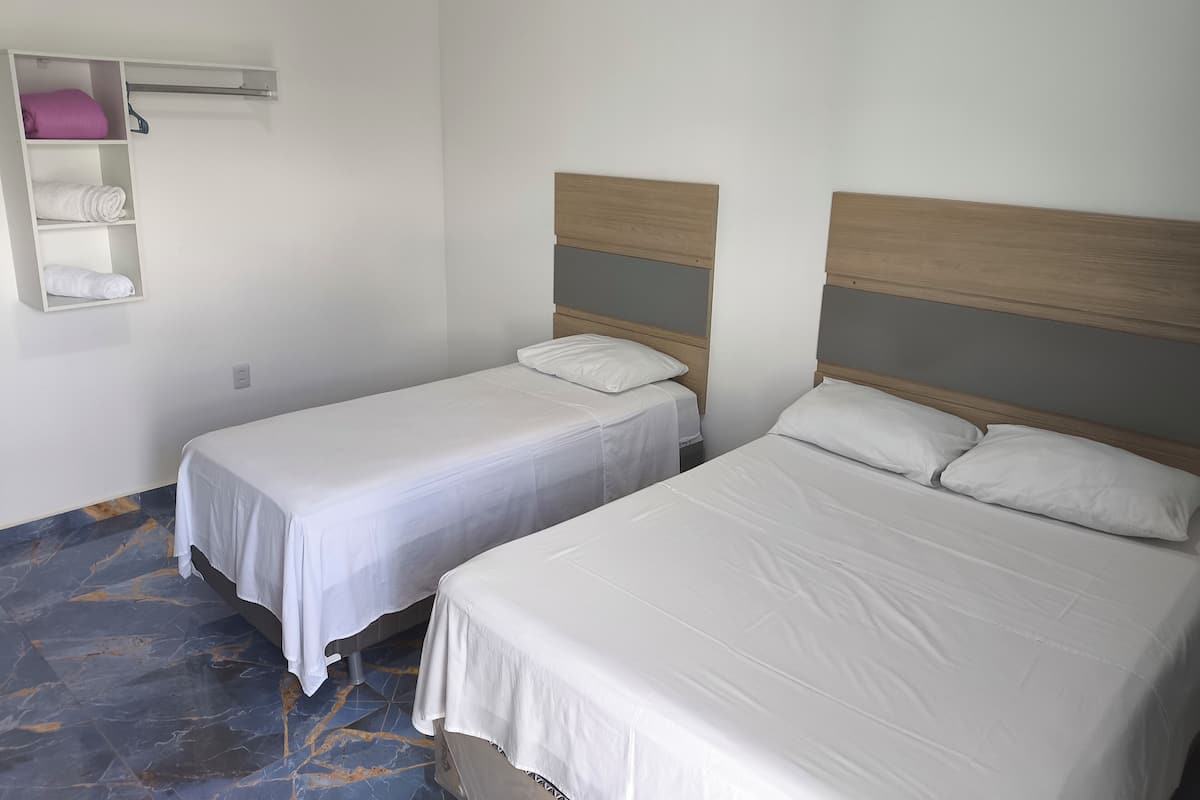 Ett hotellrum med två separata sängar, en inbyggd hylla med handdukar och ett golv med marmorliknande mönster.