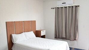 Ein Schlafzimmer mit Bett, Nachttisch und Klimaanlage.