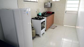 Una cocina compacta equipada con refrigerador, estufa, microondas y horno pequeño.