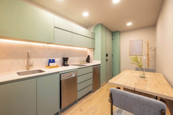 A modern kitchen with a built-in dishwasher, a coffee maker, and a small sink.