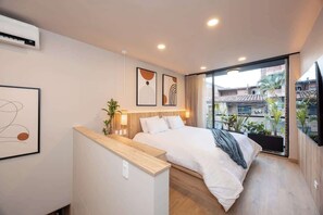 A modern bedroom with a bed, bedside table, and a large window with a city view. - Digital Nomad Paradise 1BR unit with A/C in Manila (Medellín)