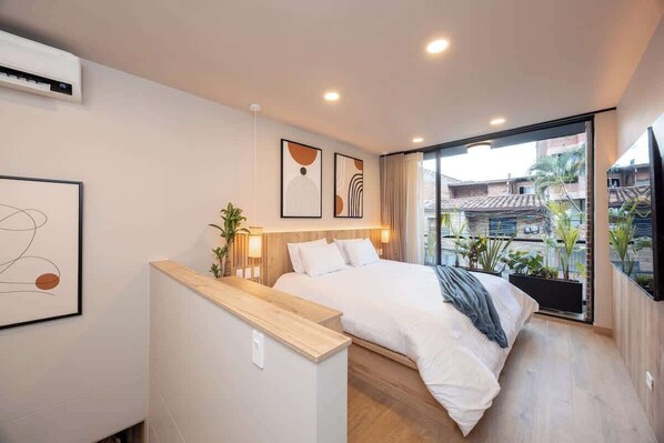 A modern bedroom with a bed, bedside table, and a large window with a city view.